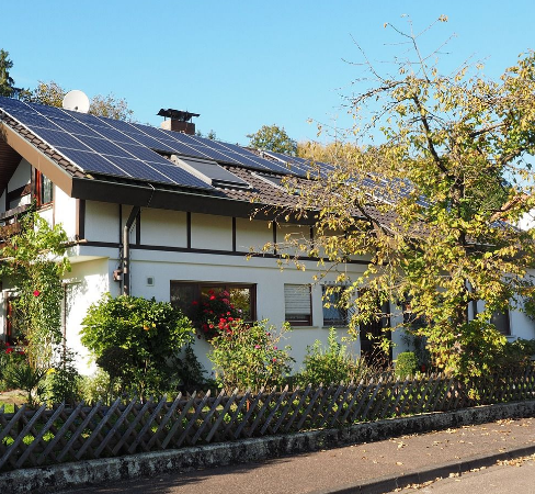 home solar panels seen on a house with green greens in front and garden in front